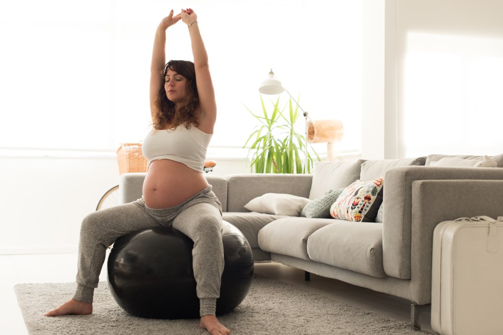 Pregnant woman doing relax exercises with a fitness pilates ball at home