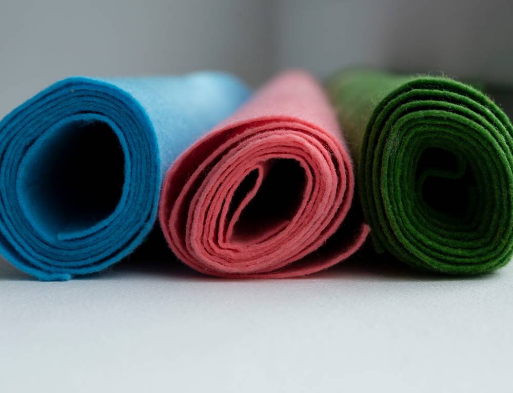 A variety of yoga mats in different materials and colors arranged side by side in a yoga studio, showcasing options like rubber, cork, and foam.