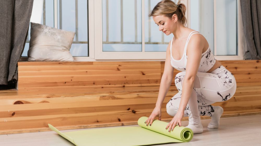 Woman folding a yoga mat after a session, showing proper care and storage.