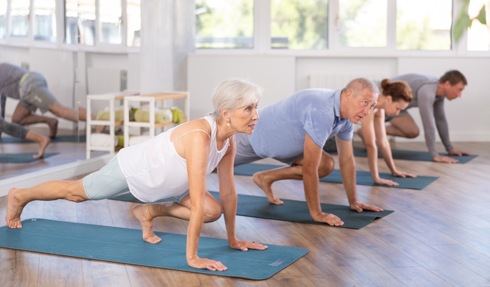 Elderly woman doing pilates exercises in group in fitness studio